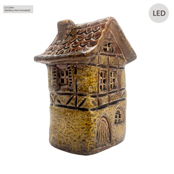 Front angle view of Cello Tales from the Village Silk Weaver’s Cottage LED ceramic house in yellow, showing detailed brickwork and illuminated windows.